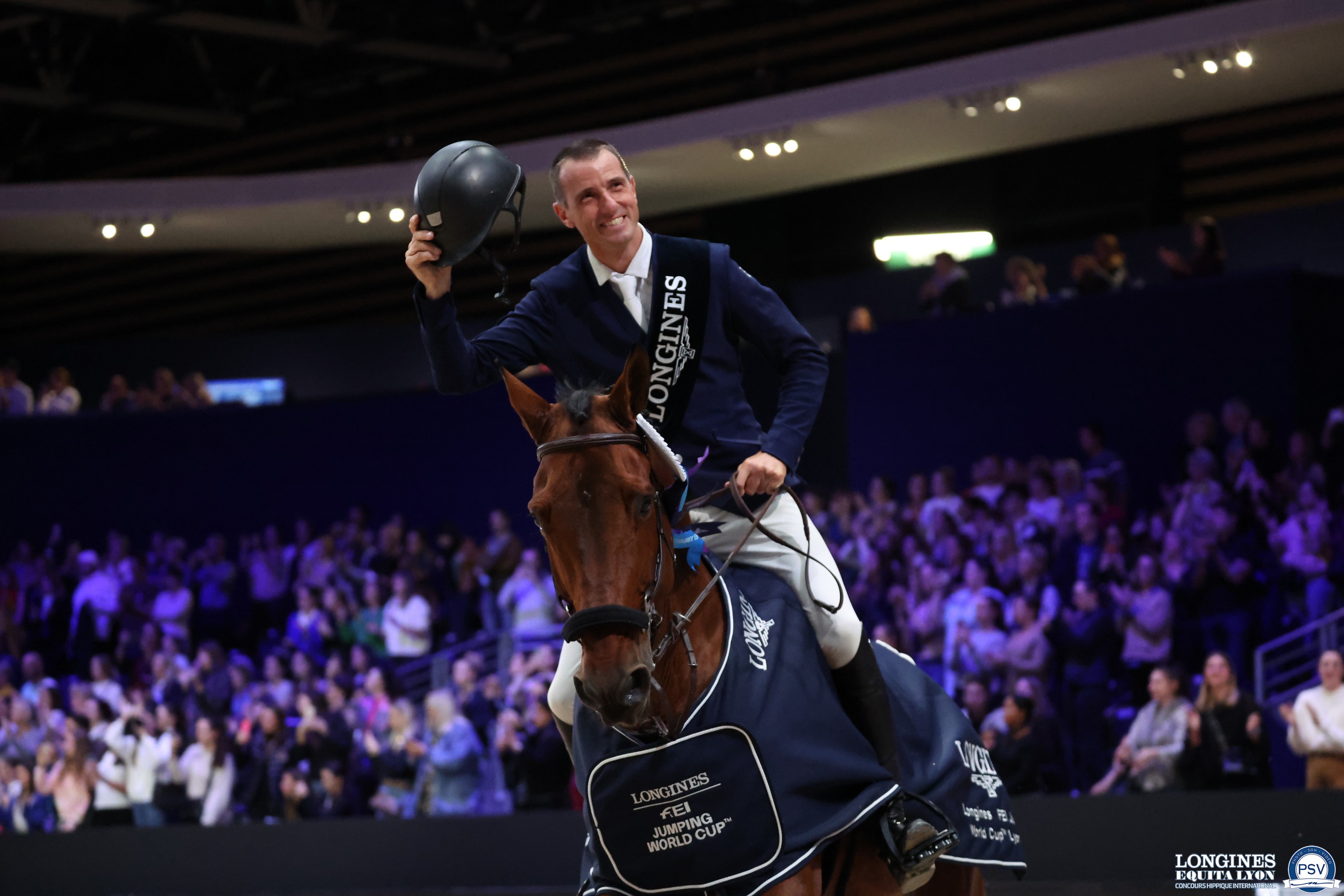 "Grégory Wathelet soulevant fièrement son casque à bout de bras lors de son tour d'honneur, "