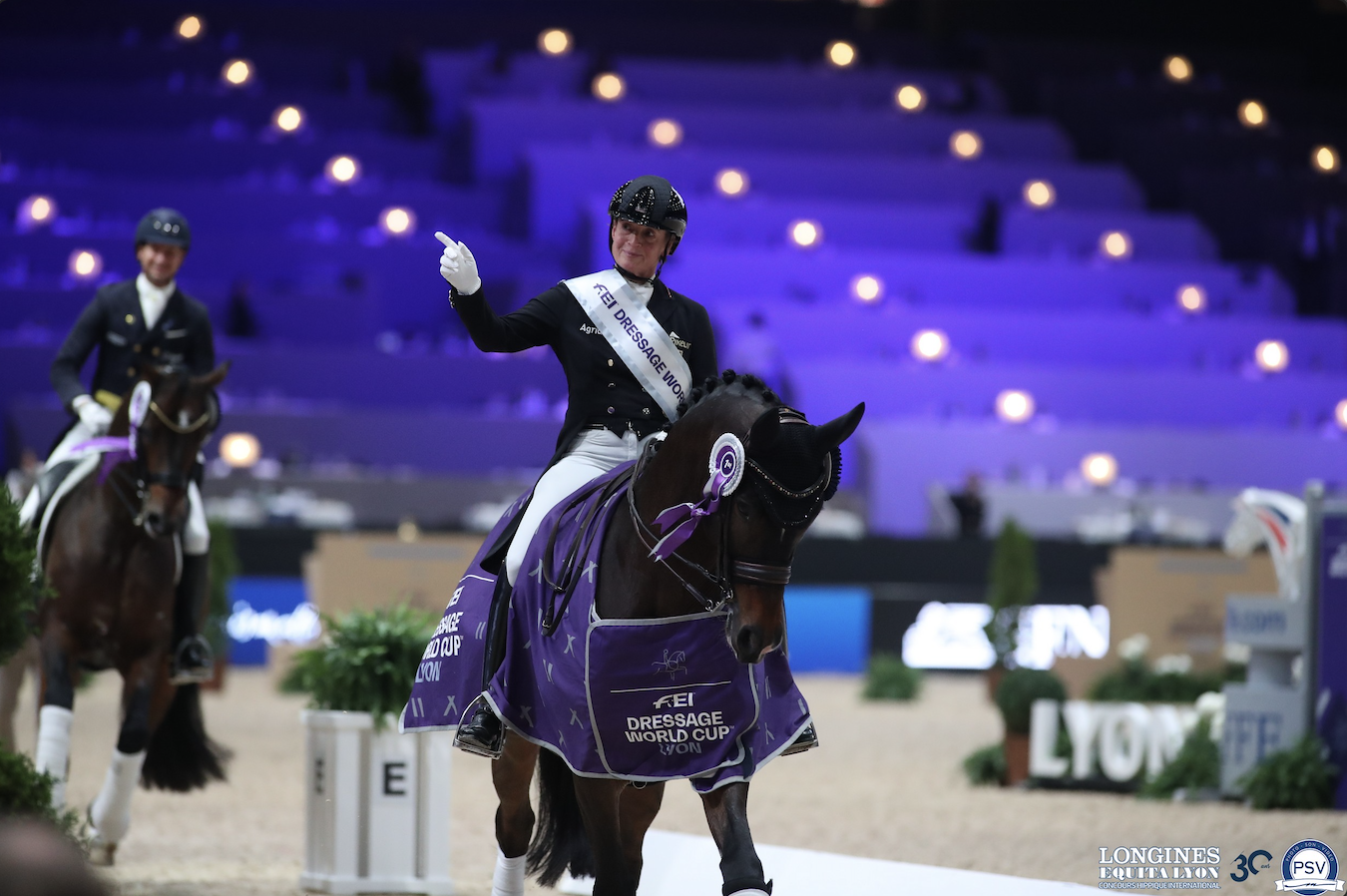 Frederic Wandre galope de face, le poing levé pour célébrer sa victoire lors du tour d'honneur